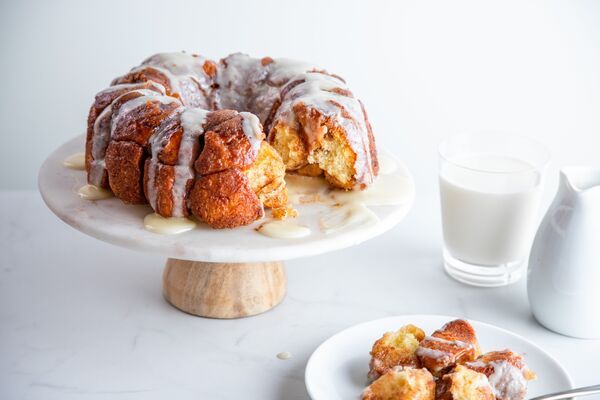 cinnamon roll monkey bread baked with C&H® Organic Raw Cane Sugar and Light Brown Sugar and drizzled with cream cheese icing next to glass of milk
